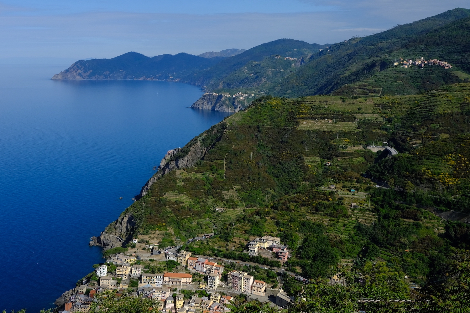 La frastagliata costa delle 5 Terre, e in basso, Riomaggiore.